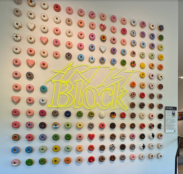 An image of the Artist Block neon sign surrounded by hundreds of donut sculptures. 