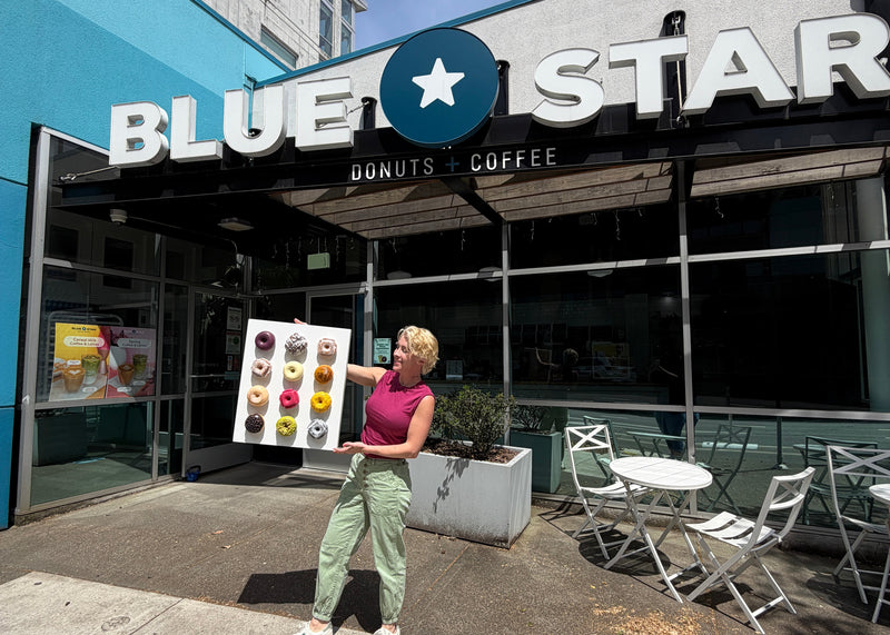 Person holding a work of art of donuts in front of Blue Star Donuts & Coffee shop